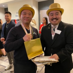 Two men in gold hats holding a gold bag